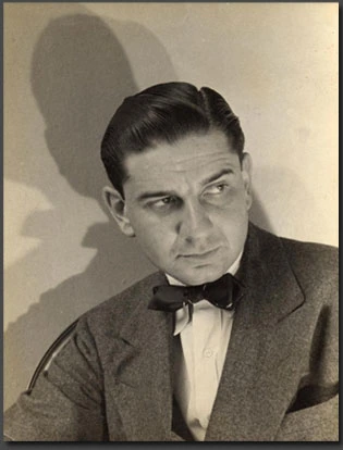 Black-and-white portrait of cartoonist Charles Addams in a suit and bow tie, looking off to the side.