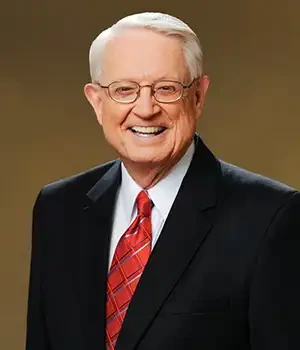 Portrait of Charles R. Swindoll smiling in a suit and red tie